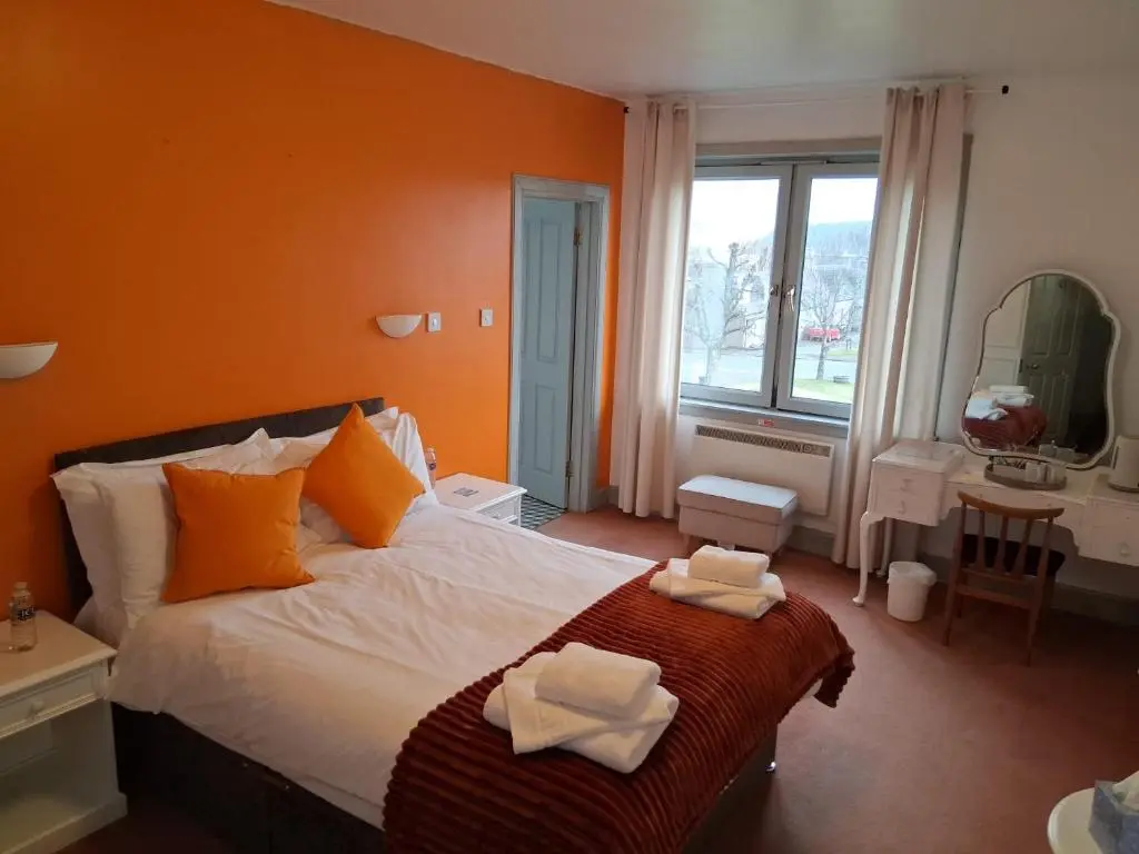 a bedroom with a bed with two towels on it at Hotel Square in Tomintoul
