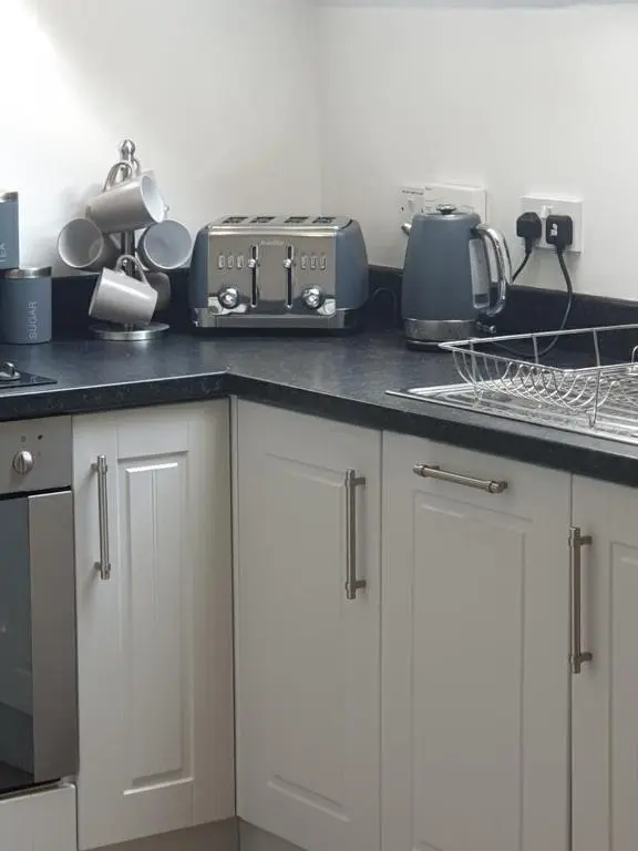 a kitchen with white cabinets and a counter top at Inchmarlo villa27 in Banchory