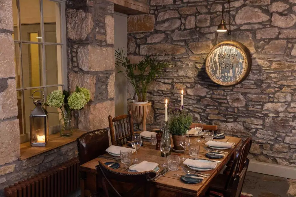 a wooden table in a room with a stone wall at Craigellachie Hotel of Speyside in Craigellachie