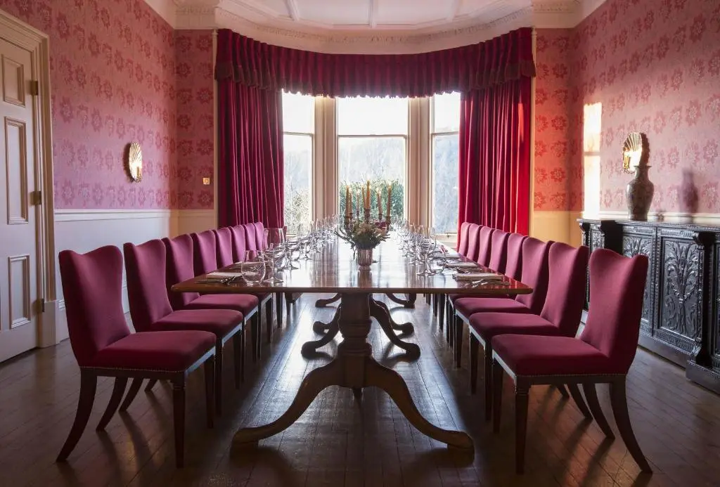 a dining room with a long table and purple chairs at Craigellachie Hotel of Speyside in Craigellachie