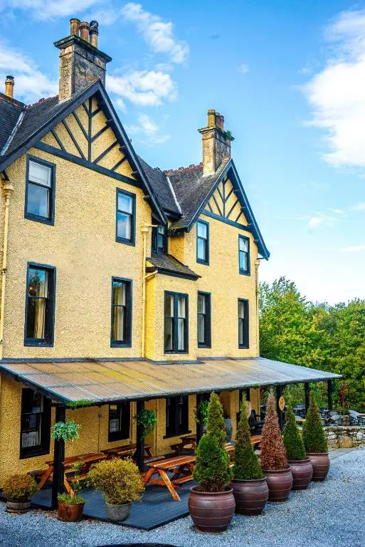 a large yellow house with plants in front of it at Craigellachie Hotel of Speyside in Craigellachie