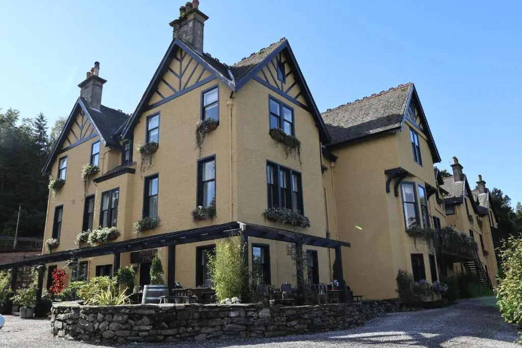 a large yellow house with a stone wall at Craigellachie Hotel of Speyside in Craigellachie