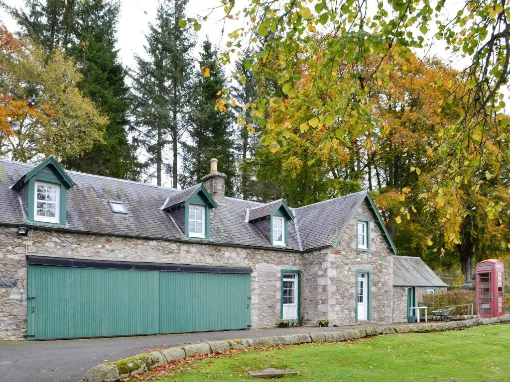 a stone house with a green garage at Inverchroskie Cottage in Enochdhu