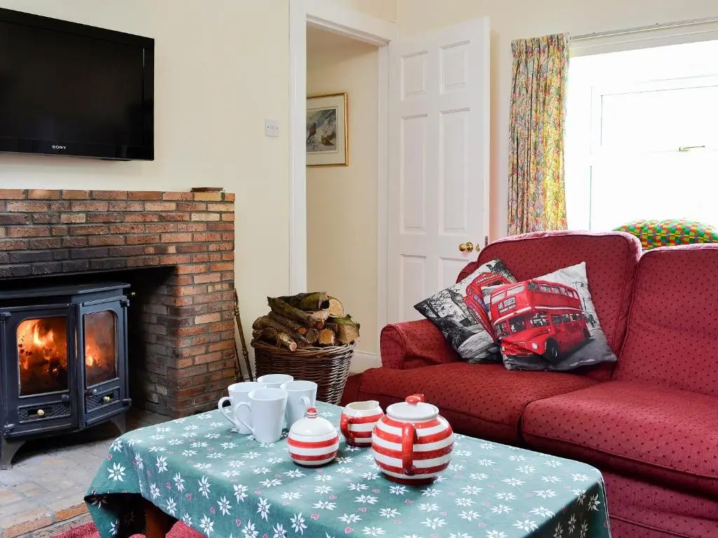 a living room with a red couch and a fireplace at Inverchroskie Cottage in Enochdhu