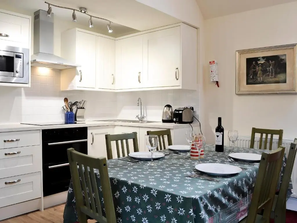 a kitchen with a table with a table cloth on it at Inverchroskie Cottage in Enochdhu