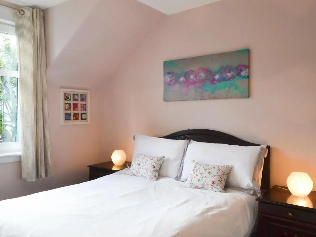 a bedroom with a white bed with two pillows at Viewhill Villa in Inverness