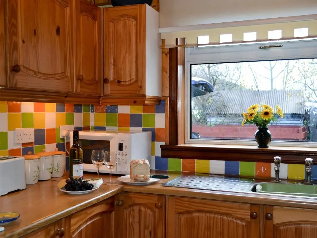 a kitchen with a counter with a microwave and a window at Riverside Cottage in Drumnadrochit