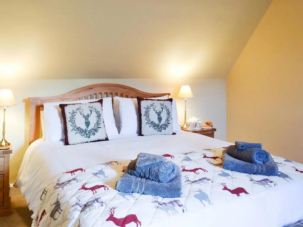 a bedroom with a bed with blue towels on it at Glebe Cottage in Urray