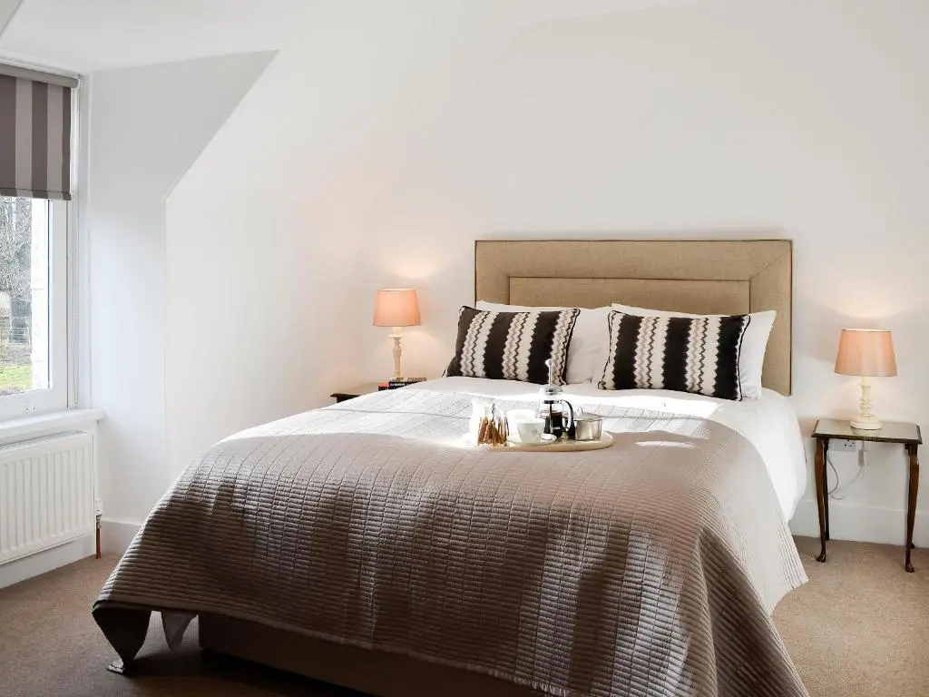 a bedroom with a large bed with a tray on it at The Coach House in Alford