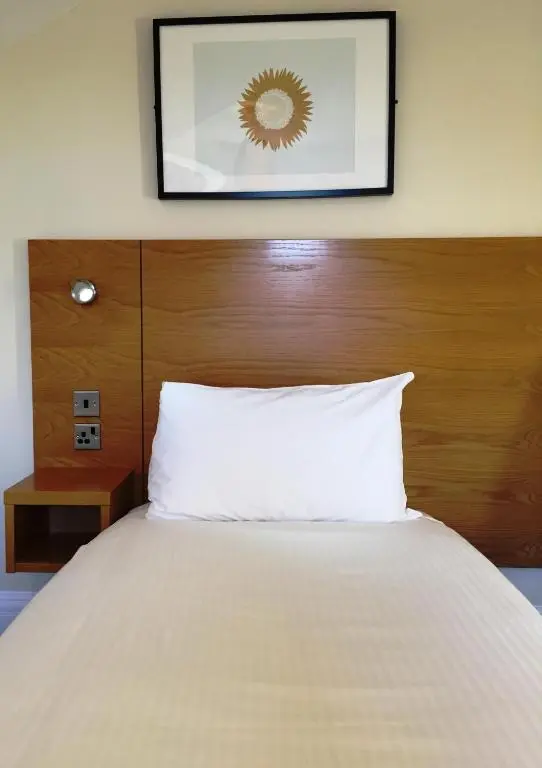 a bed with a wooden headboard and a white pillow at Stotfield Hotel in Lossiemouth