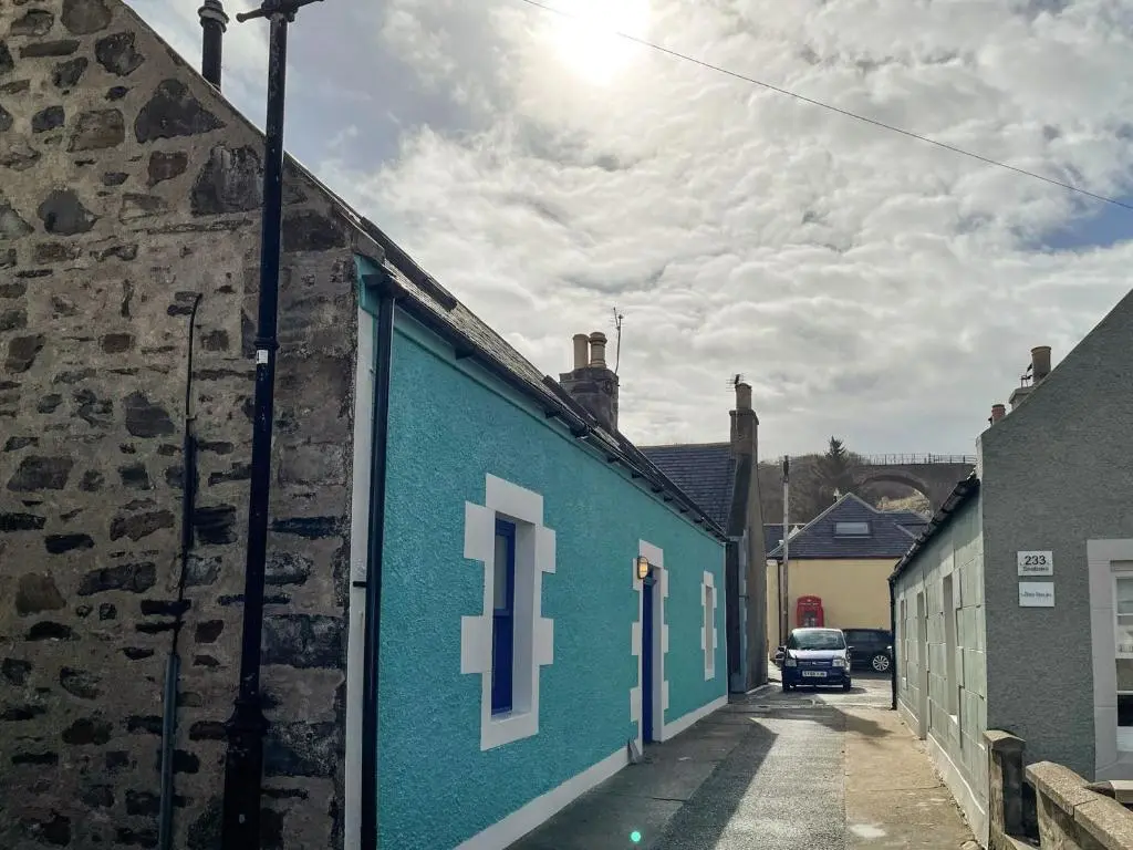 a blue building with a car parked on a street at Jebel in Cullen
