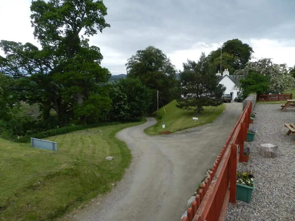 a winding road with a fence and a house at Clunebeg Lodge in Drumnadrochit