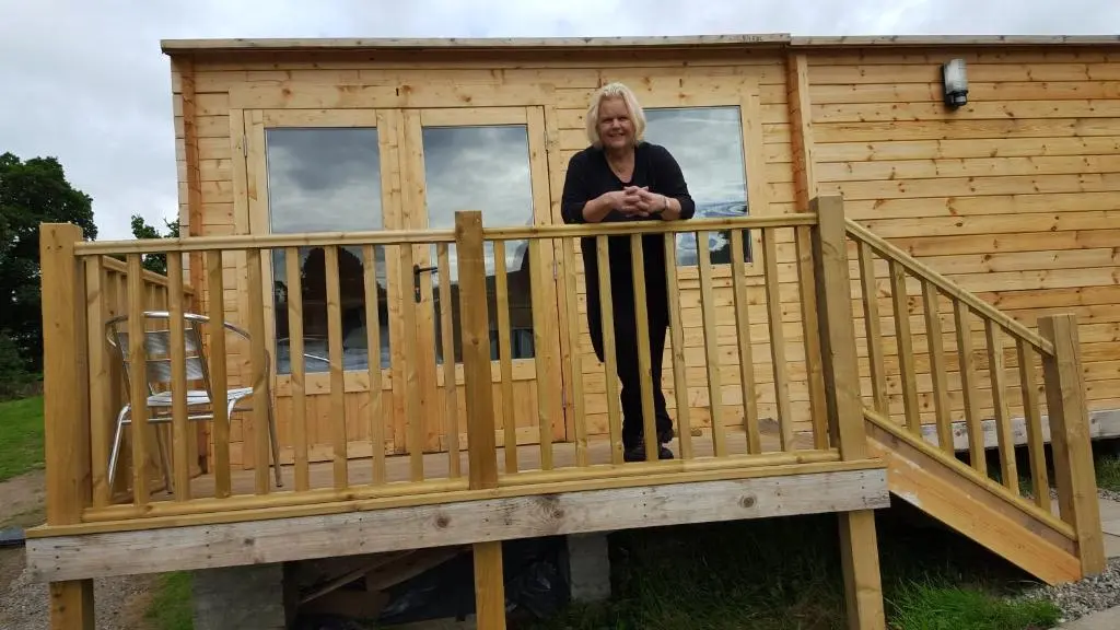 a woman standing on the deck of a tiny house at Clunebeg Lodge in Drumnadrochit