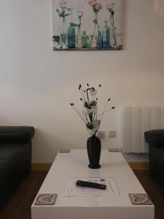 a table with a vase with flowers on it at Millburn Apartments in Inverness