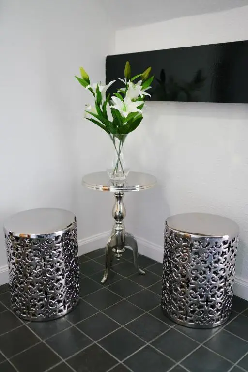 a vase of flowers on a table with two stools at Millburn Apartments in Inverness
