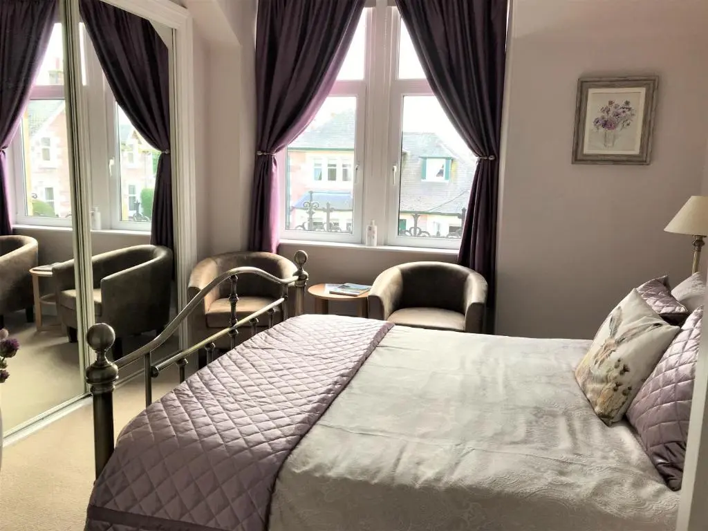 a bedroom with a bed and two windows at The Castle B&B in Inverness