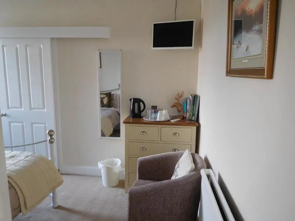 a bedroom with a chair and a dresser and a bed at The Castle B&B in Inverness