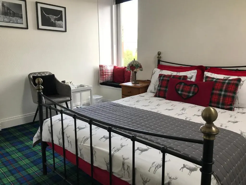 a bedroom with a bed and a chair and a window at The Castle B&B in Inverness