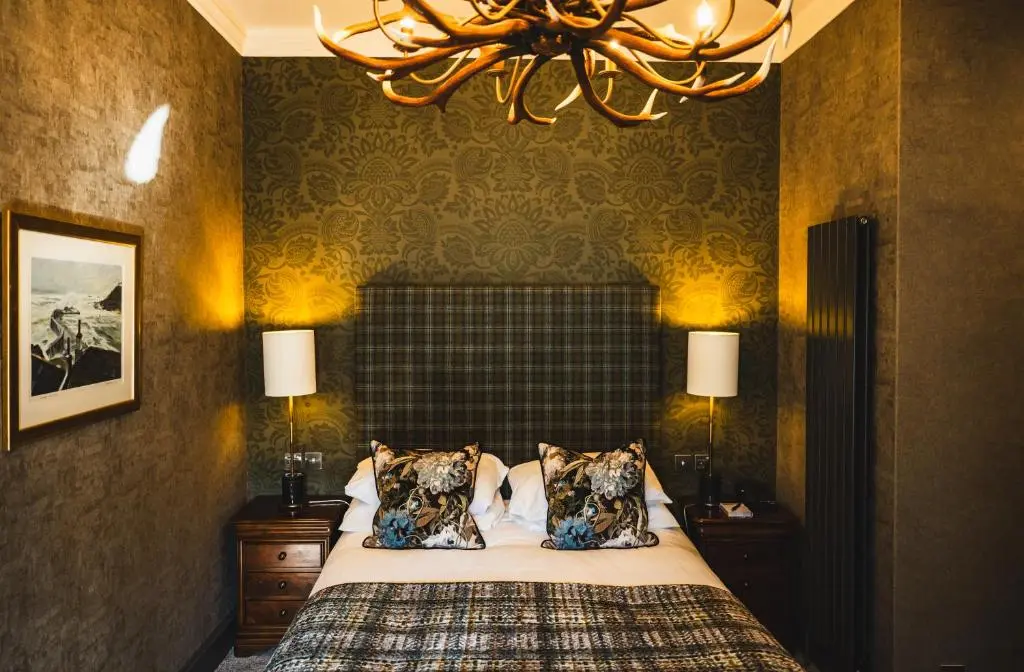 a bedroom with a bed and a chandelier at Maryculter House in Maryculter