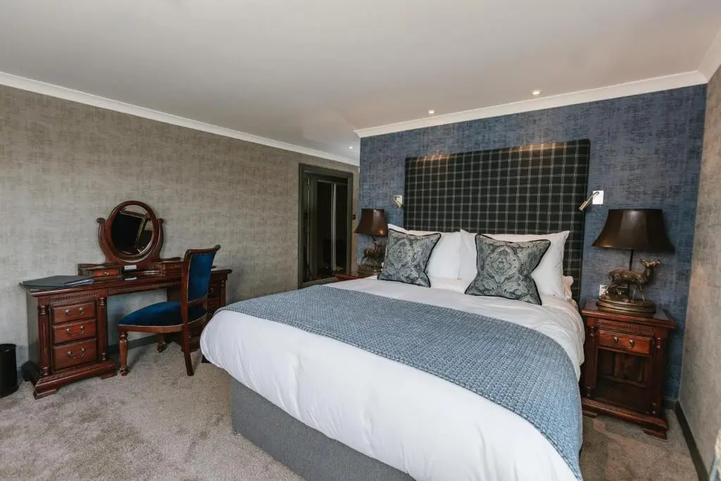 a bedroom with a bed and a desk and a mirror at Maryculter House in Maryculter