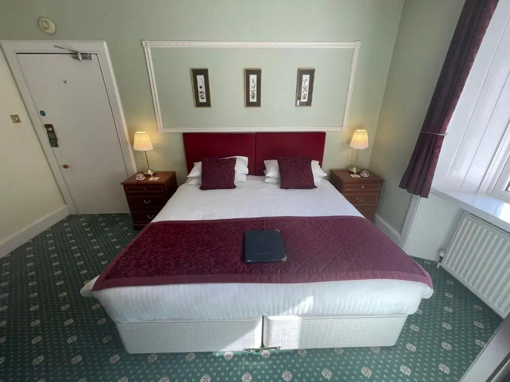 a bedroom with a large bed with a tablet on it at Ravenscourt House, Guest House in Grantown on Spey