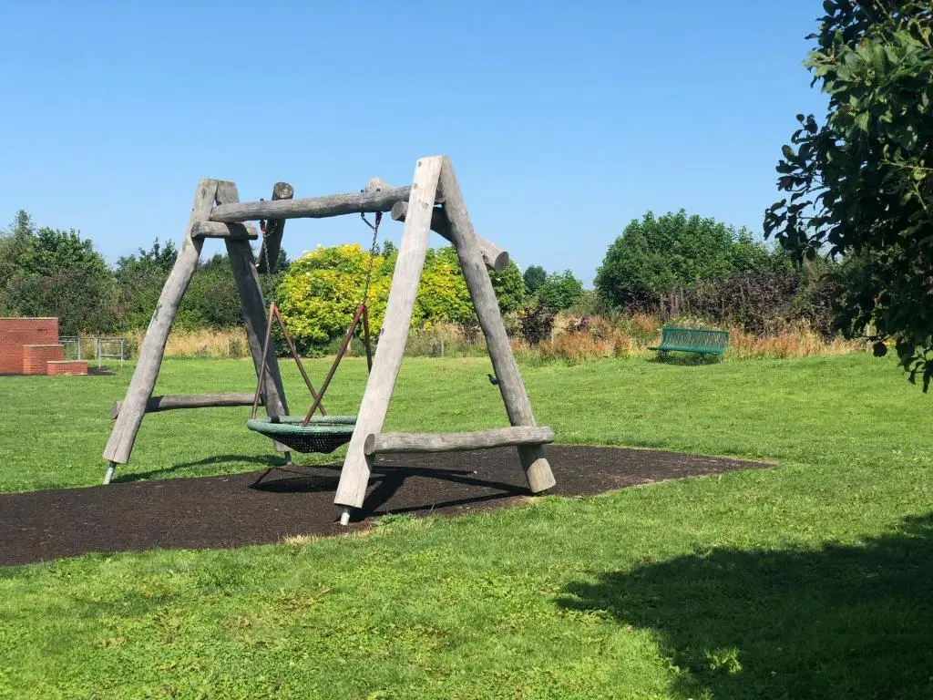 a wooden swing set in a field of grass at One-Bedroom Apartment - Wyvis Free Parking in Inverness