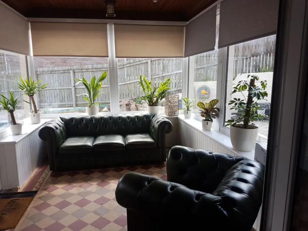 a living room with leather couches and potted plants at Cromarty View Guest House Accommodations & B&B in Dingwall
