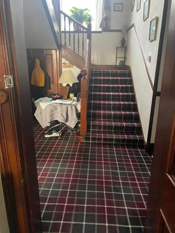 a hallway with a carpeted staircase with a table at Cromarty View Guest House Accommodations & B&B in Dingwall