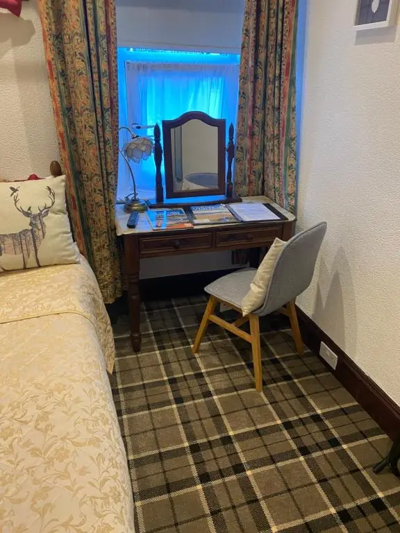 a bedroom with a desk with a mirror and a chair at Cromarty View Guest House Accommodations & B&B in Dingwall