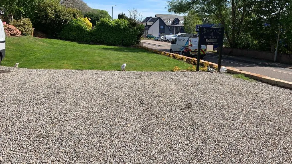 a gravel driveway with a sign and a street at Cromarty View Guest House Accommodations & B&B in Dingwall
