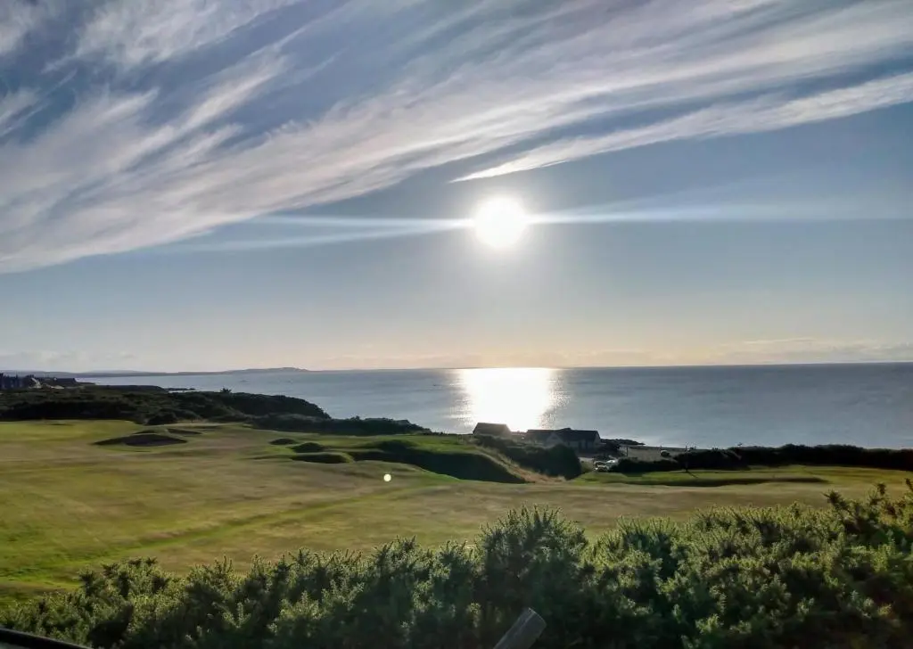 a golf course with the sun setting over the ocean at Marine Hotel in Buckie