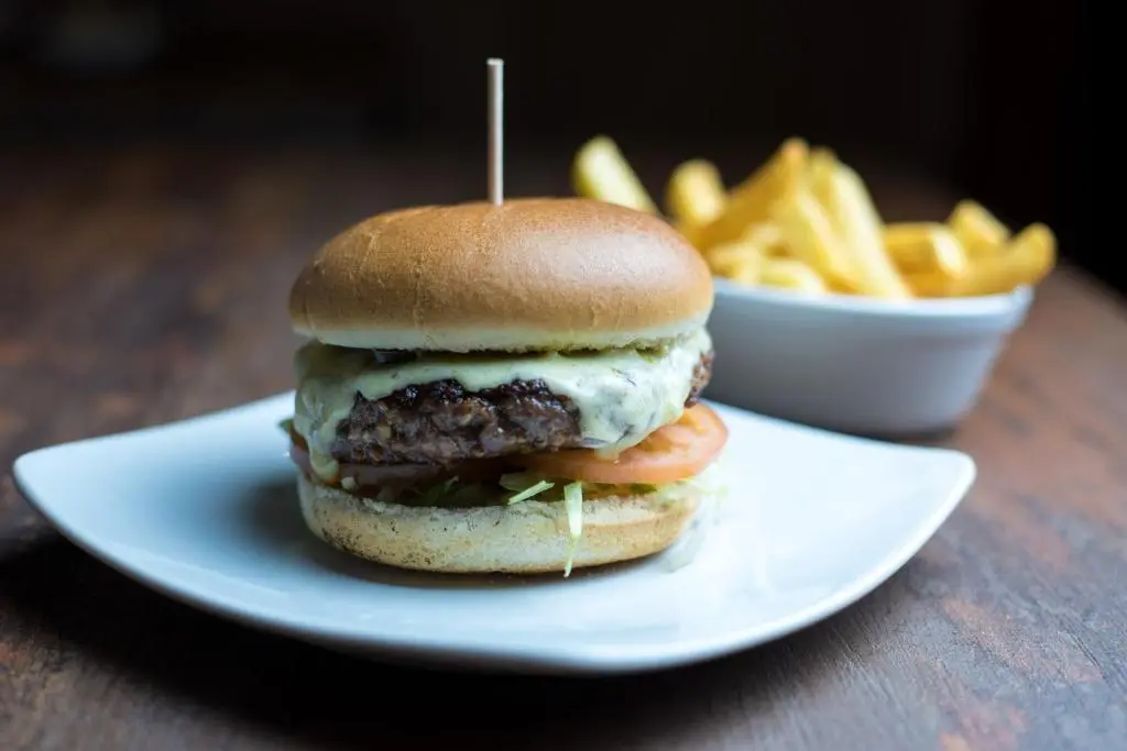 a hamburger on a plate with a bowl of fries at Laichmoray Hotel in Elgin