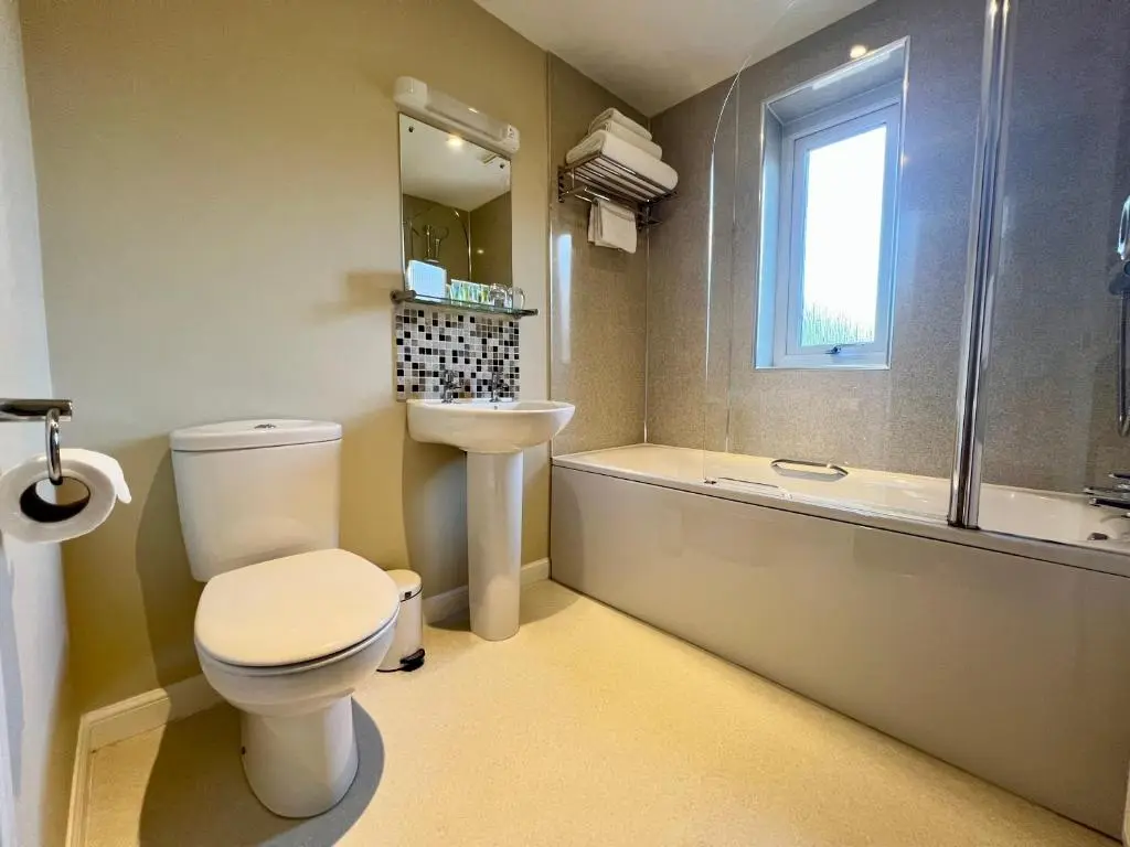 a bathroom with a toilet and a sink and a tub at Laichmoray Hotel in Elgin
