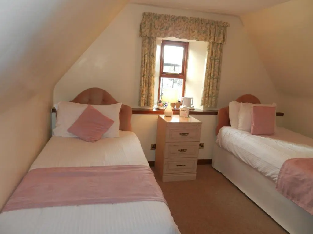 a attic bedroom with two beds and a window at Mansfield Castle Hotel in Tain