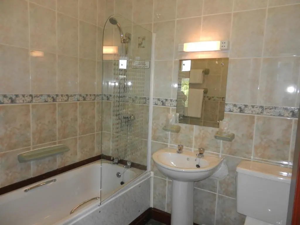 a bathroom with a sink and a toilet and a tub and a sink at Morangie Hotel Tain in Tain