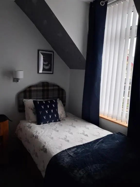 a bedroom with a bed with a blue and white comforter at Fairfield Townhouse Guest House in Inverness