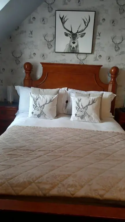 a bedroom with a bed with a deer on the wall at Fairfield Townhouse Guest House in Inverness
