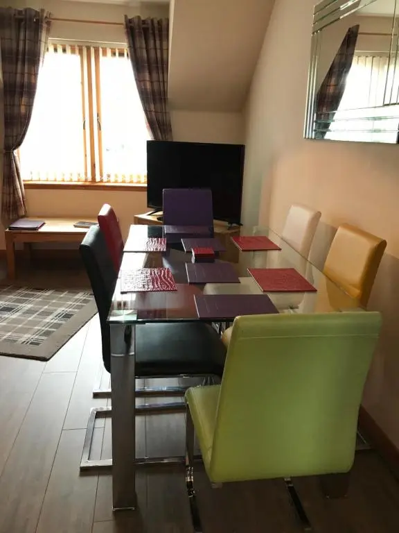 a room with a table with chairs and books on it at Cairngorm Mountain View in Aviemore
