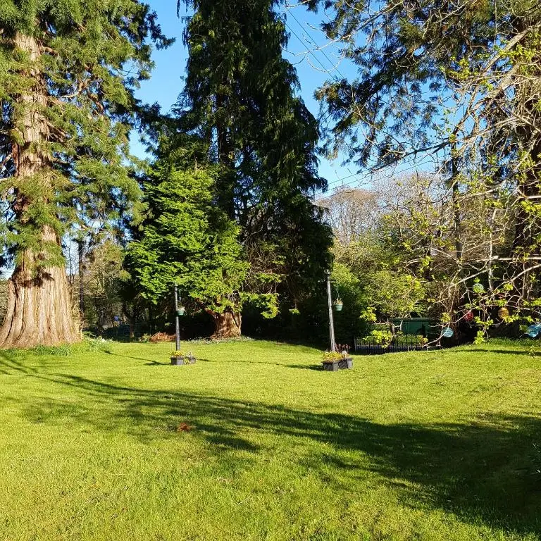a park with two benches in the grass with trees at Kilmichael House in Drumnadrochit