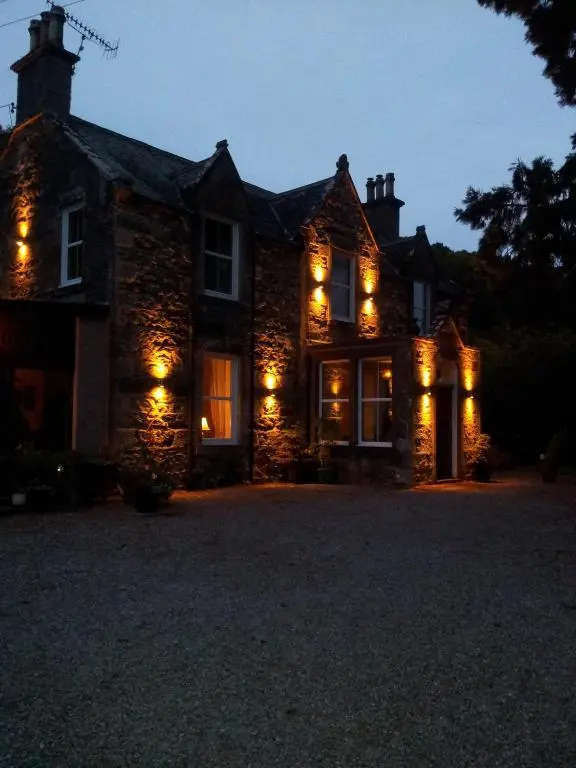 a stone house with lights on the front of it at Kilmichael House in Drumnadrochit