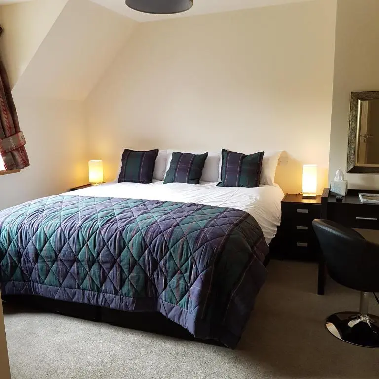 a bedroom with a bed and a desk with two lamps at Kilmichael House in Drumnadrochit