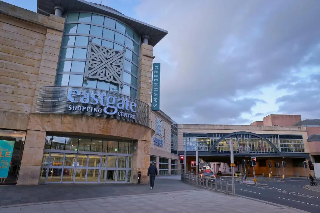 a man walking in front of a shopping center at Inverness Youth Hostel in Inverness