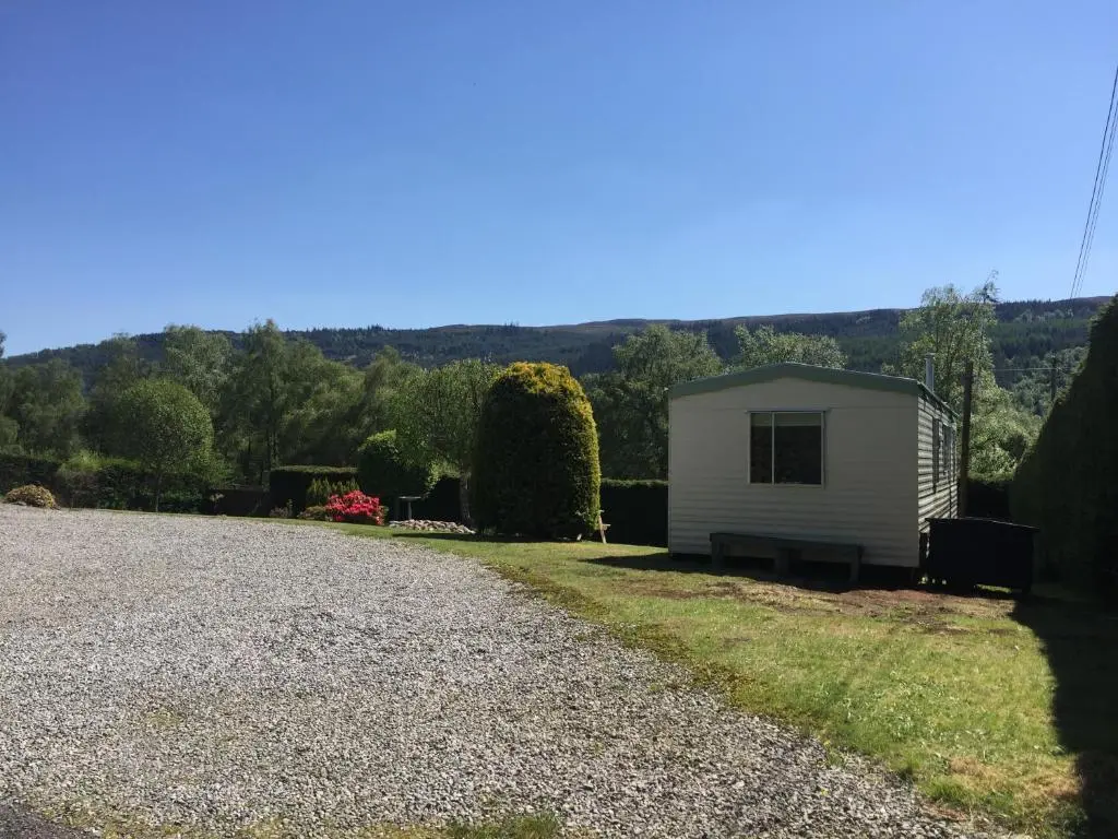 a small white building on the side of a gravel road at Forest View - Adults Only - Maximum 2 Guests in Drumnadrochit