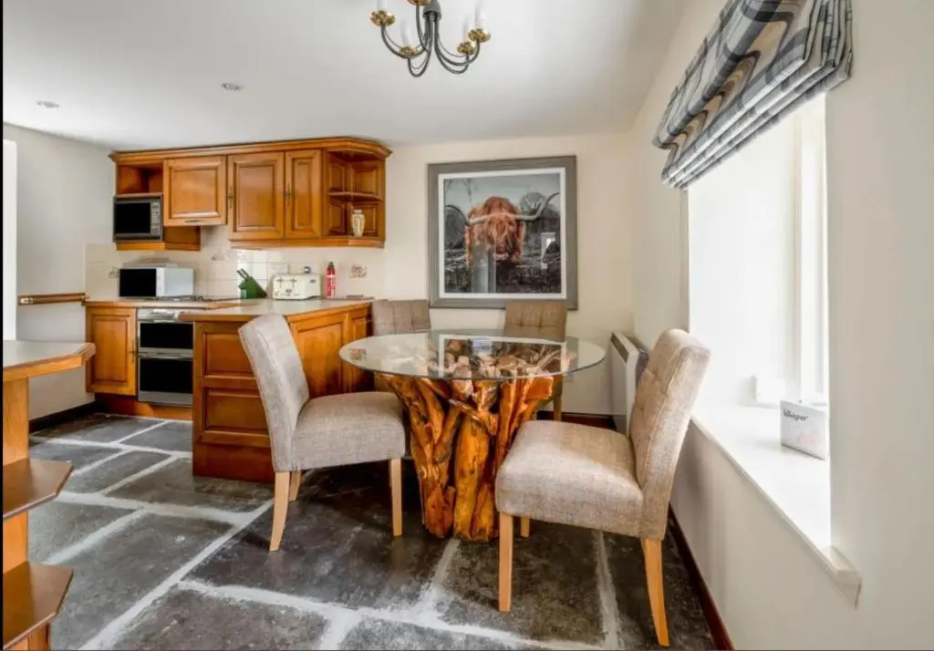 a kitchen with a table and two chairs and a counter at Loch Ness Cottages in Brackla