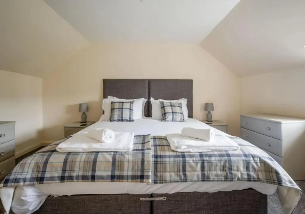 a bedroom with a large bed with two towels on it at Loch Ness Cottages in Brackla