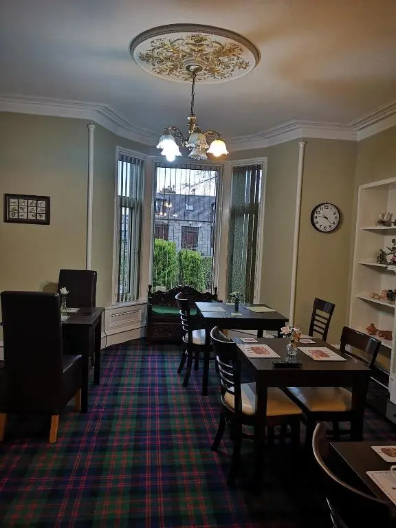 a dining room with tables and chairs and a chandelier at Granville Guest House in Dyce
