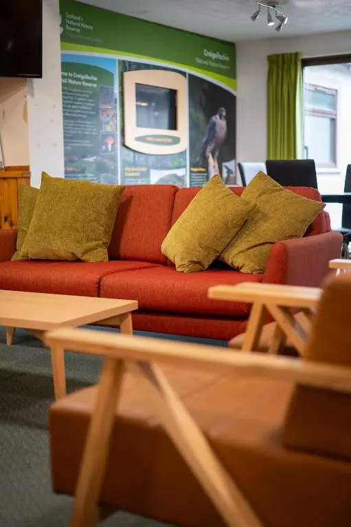 a red couch with yellow pillows in a living room at Aviemore Youth Hostel in Aviemore