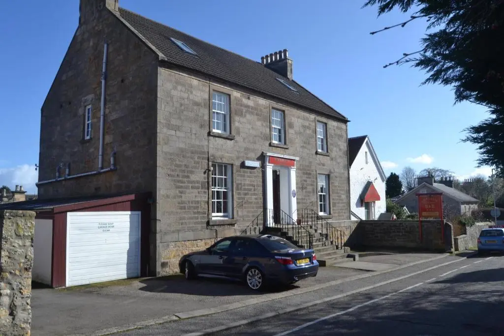 a car parked in front of a brick house at Southbank Guesthouse in Elgin