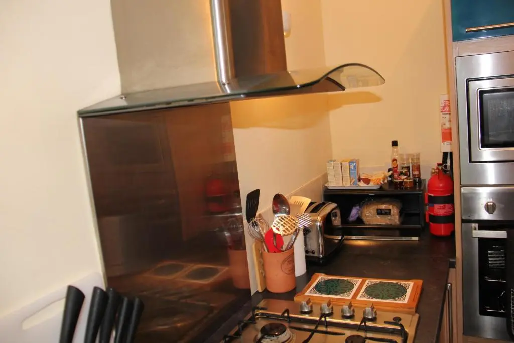 a kitchen counter with a stove and a microwave at Reay Street Apartment in Inverness