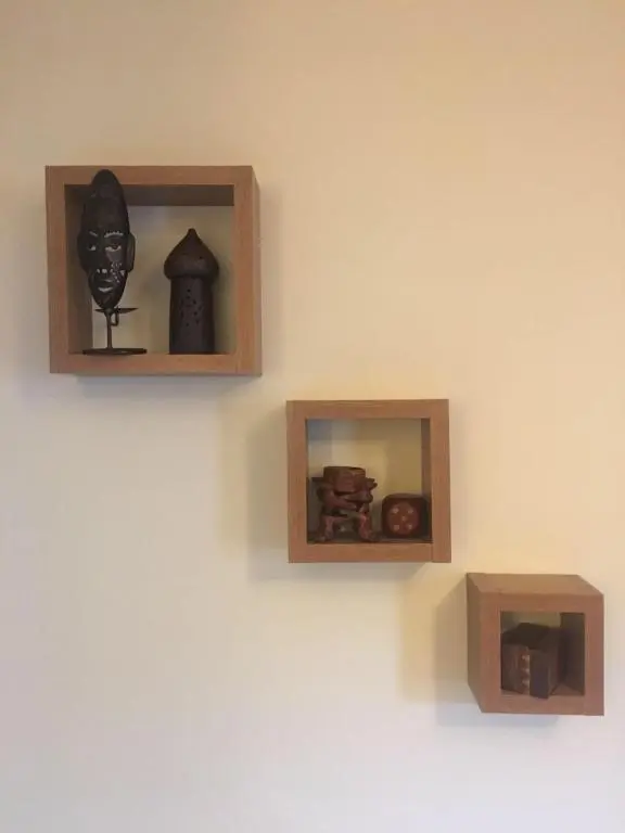 a wall with two wooden shelves with different items on it at Reay Street Apartment in Inverness